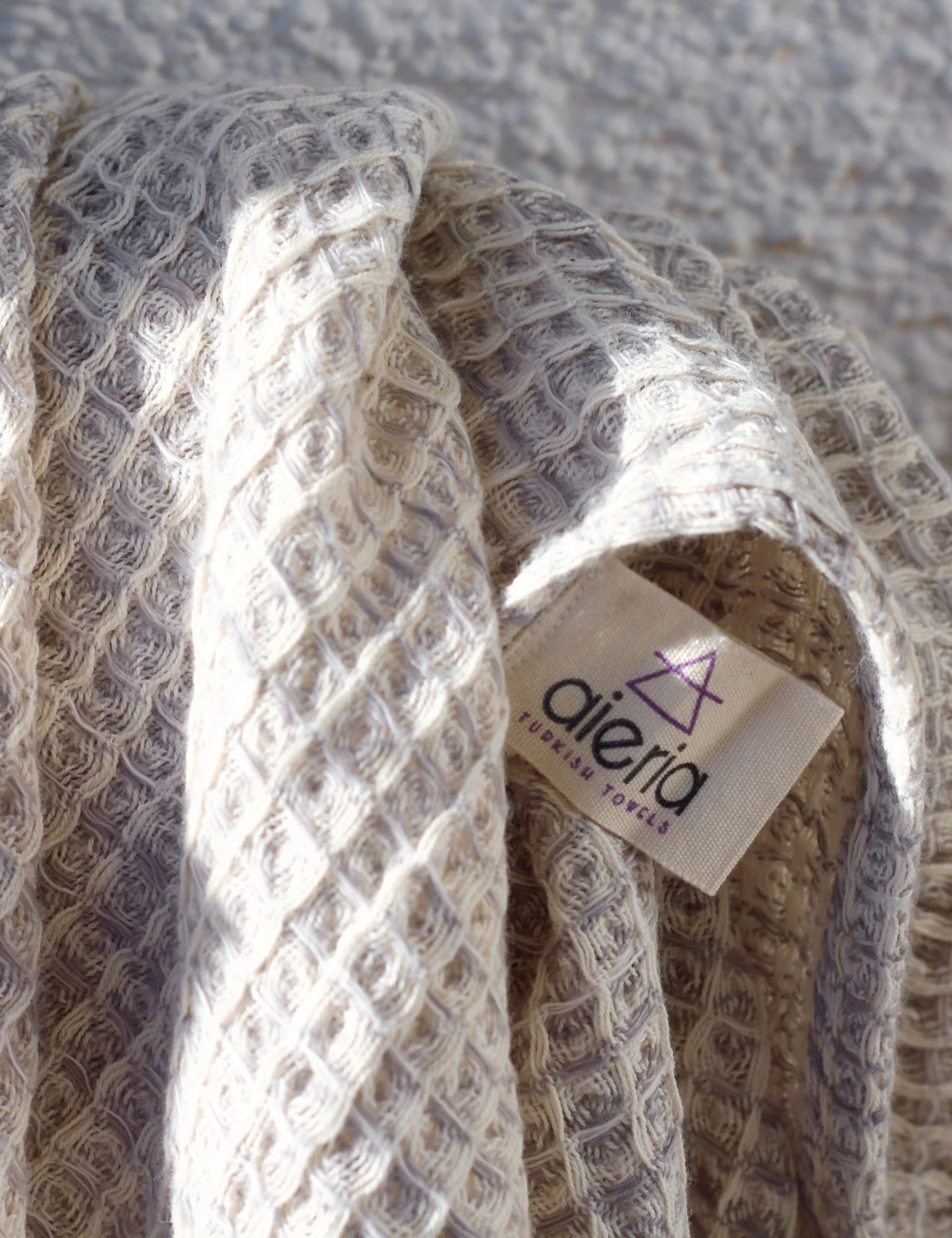Close-up of gray waffle weave hammam towel with label, showcasing its soft, textured surface.