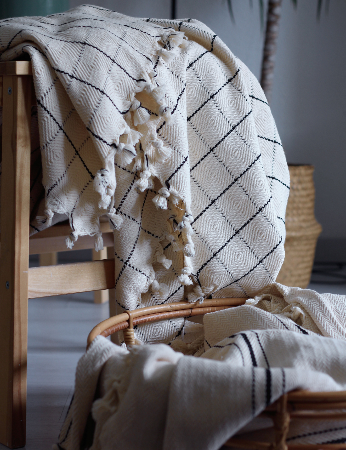 Cream handwoven cotton throw blanket with windowpane pattern draped over a chair, enhancing home decor with timeless style.